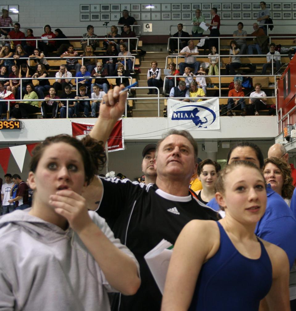 Gardner High swimmers Jane Ehret, left, and Taylor Strachan anxiously watch the times and scores with coach Don Lemieux at the state meet at Harvard University in 2010.
