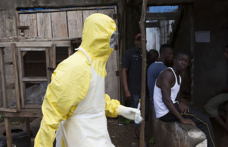 A health worker in protective equipment carries a sample taken from the body of someone who is suspected to have died from Ebola virus, near Rokupa Hospital, Freetown October 6, 2014. REUTERS/Christopher Black/WHO/Handout via Reuters