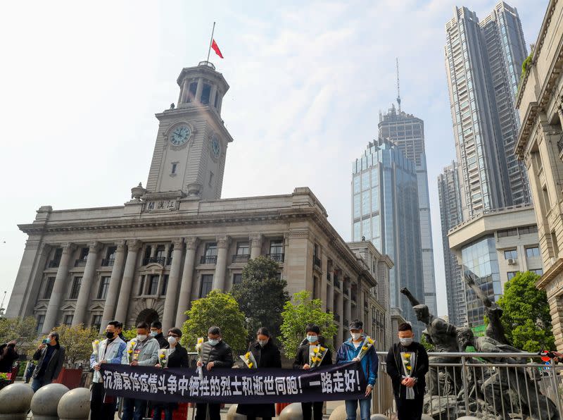 People observe a moment of silence outside Hankou Customs House where the Chinese national flag flies at half mast, in Wuhan