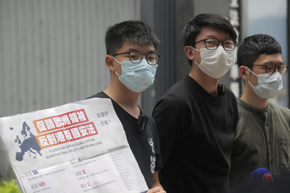 Pro-democracy activists, Joshua Wong, left, Sunny Cheung, center, and Nathan Law holding a placard, speak to media to urge the European leaders against national security law for Hong Kong outside the Legislative Council, in Hong Kong, Wednesday, June 3, 2020. British Prime Minister Boris Johnson says his country stands ready to open the door to close to 3 million Hong Kong citizens if China enacts a national security law for the city. He said in a local newspaper column that the law would curtail freedoms and has many in Hong Kong fearing for their way of life. (AP Photo/Kin Cheung)