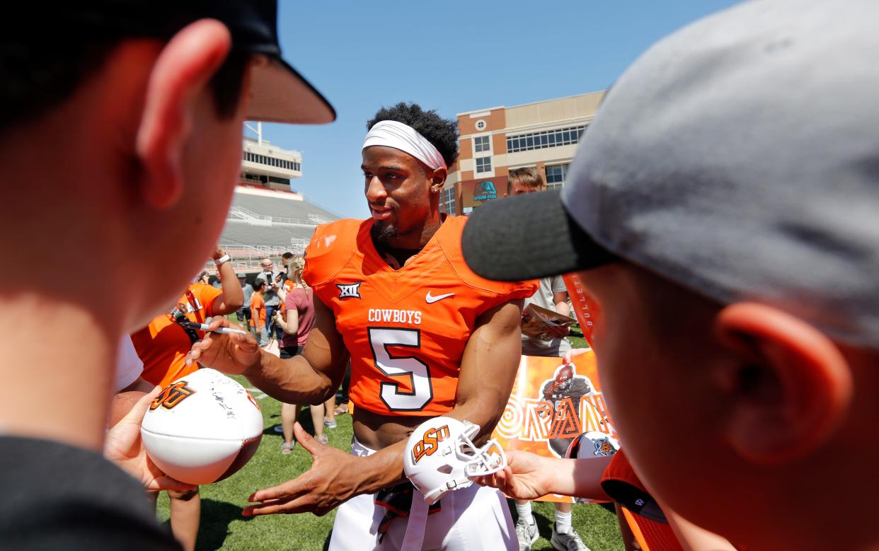Former Oklahoma State running back Justice Hill signs autographs on the field after OSU's spring game in April 2018.
