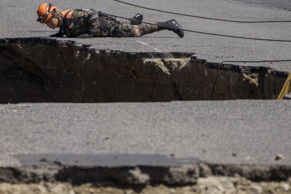 Un rescatista del Ejército de Guatemala inspecciona un sumidero en Villa Nueva, Guatemala, el martes 27 de septiembre de 2022. Se estaban realizando esfuerzos de búsqueda de una madre y su hija que desaparecieron cuando su vehículo cayó a un enorme socavón al desmoronarse una calle. (Foto AP/Moisés Castillo)