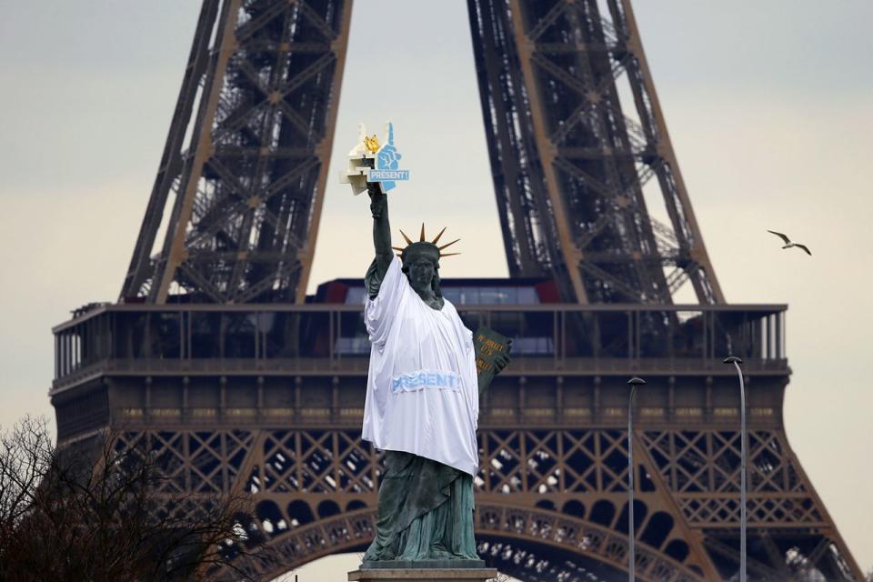 <p>Eine Miniaturkopie der amerikanischen Freiheitsstatue wurde in Frankreichs Hauptstadt Paris, direkt vor dem Eiffelturm, errichtet. Sie trägt ein T-Shirt und einen Schaumstoff-Handschuh, die jeweils das Wort „Present“ aufgedruckt haben. Der Fernsehmoderator Nicolas Hulot ist mitverantwortlich für die Errichtung der Statue, die ein Zeichen für den Umweltschutz sein soll. (Bild: Francois Mori/AP) </p>