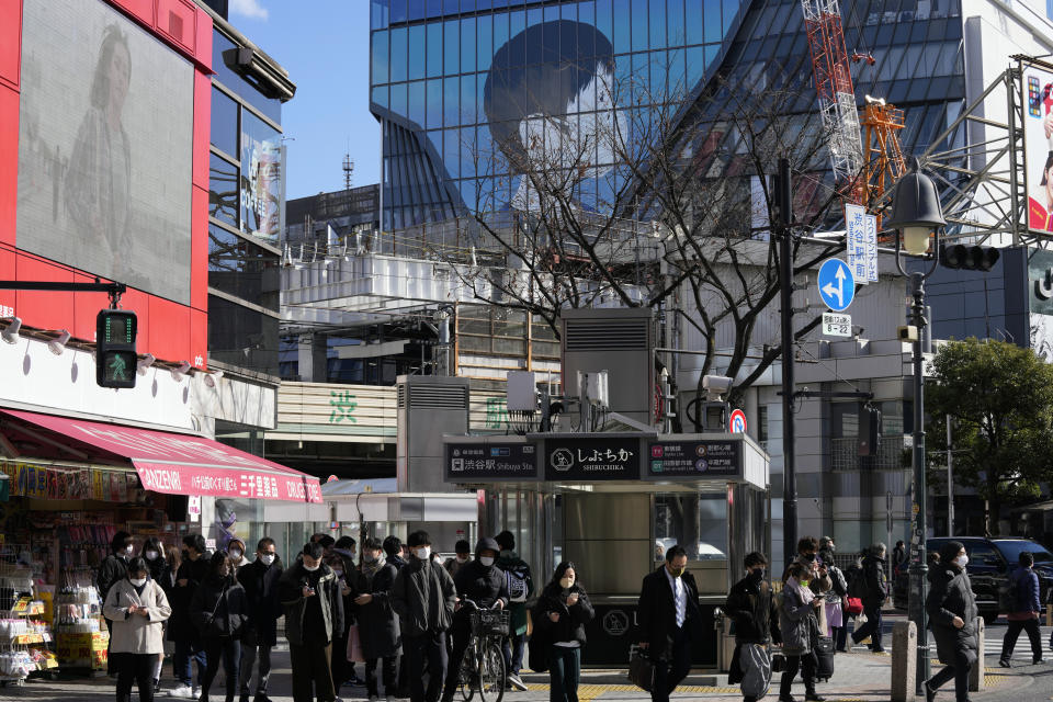 People wearing protective masks to help curb the spread of the coronavirus walk along a pedestrian crossing Friday, Jan. 21, 2022, in Tokyo. Restaurants and bars will close early in Tokyo and a dozen other areas across Japan beginning Friday as the country widens COVID-19 restrictions due to the omicron variant causing cases to surge to new highs in metropolitan areas. (AP Photo/Eugene Hoshiko)