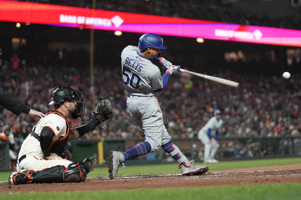 Los Angeles Dodgers' Mookie Betts (50) hits an RBI single in front of San Francisco Giants catcher Joey Bart during the seventh inning of a baseball game in San Francisco, Monday, April 10, 2023. (AP Photo/Jeff Chiu)