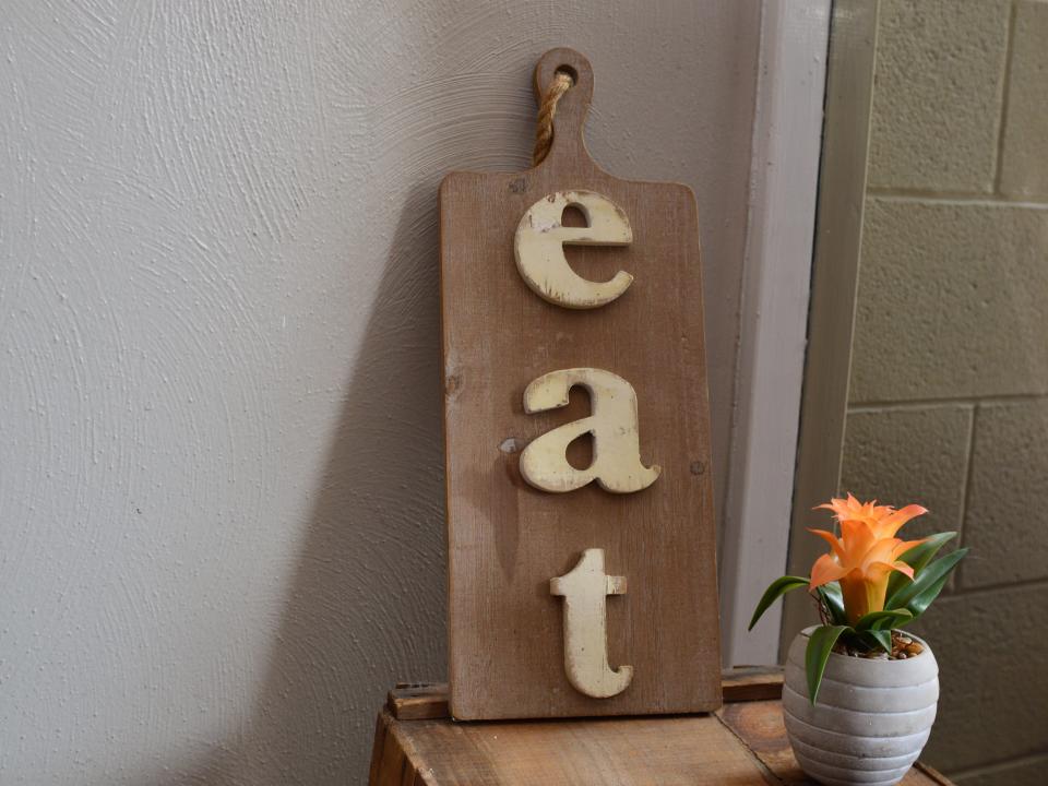 A brown cutting board with the word "Eat" on it in a kitchen