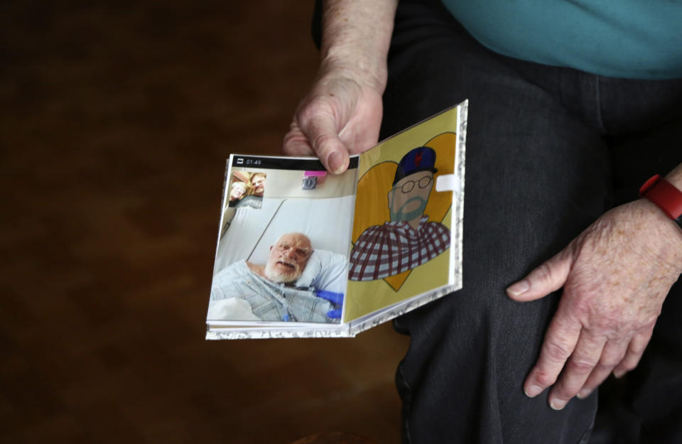 Peg Walter holds a photograph and a portrait of her late husband in the Queens borough of New York, Tuesday, March 30, 2021. John Walter died of the coronavirus in May 2020. (AP Photo/Jessie Wardarski)