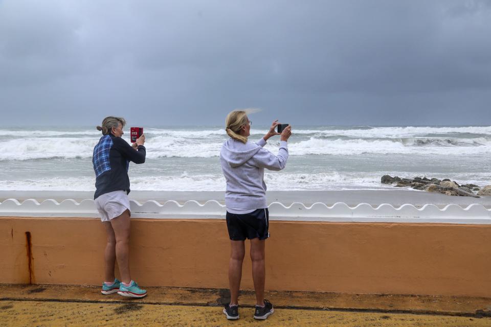 Women take pictures of crashing waves Wednesday at Midtown Beach as Tropical storm Nicole approaches the east coast of Florida.
