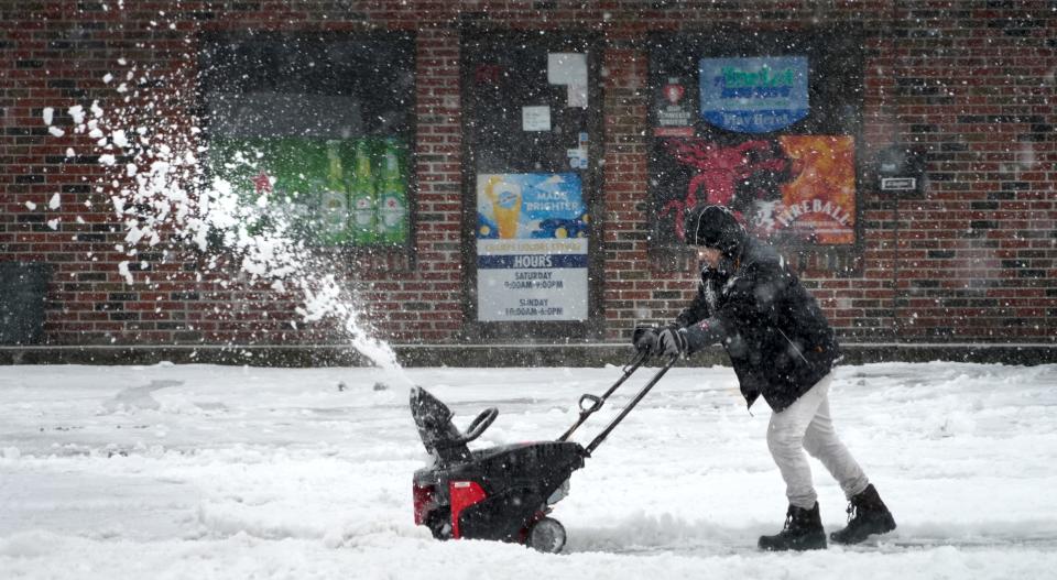 A small snowblower struggles to throw Sunday's slushy mix from the fronts of businesses on Clinton Street in Woonsocket.