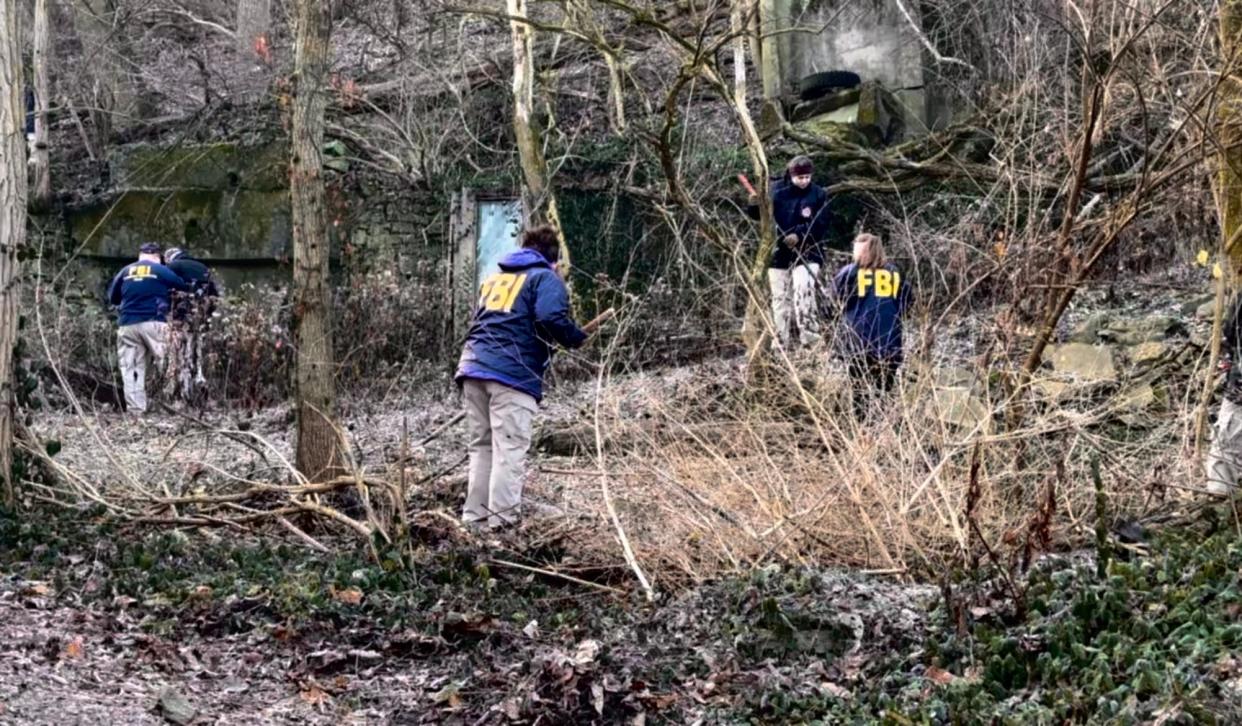 The FBI evidence response team searches a wooded area in North Fairmount Wednesday where the dismembered body of a woman was found in November.