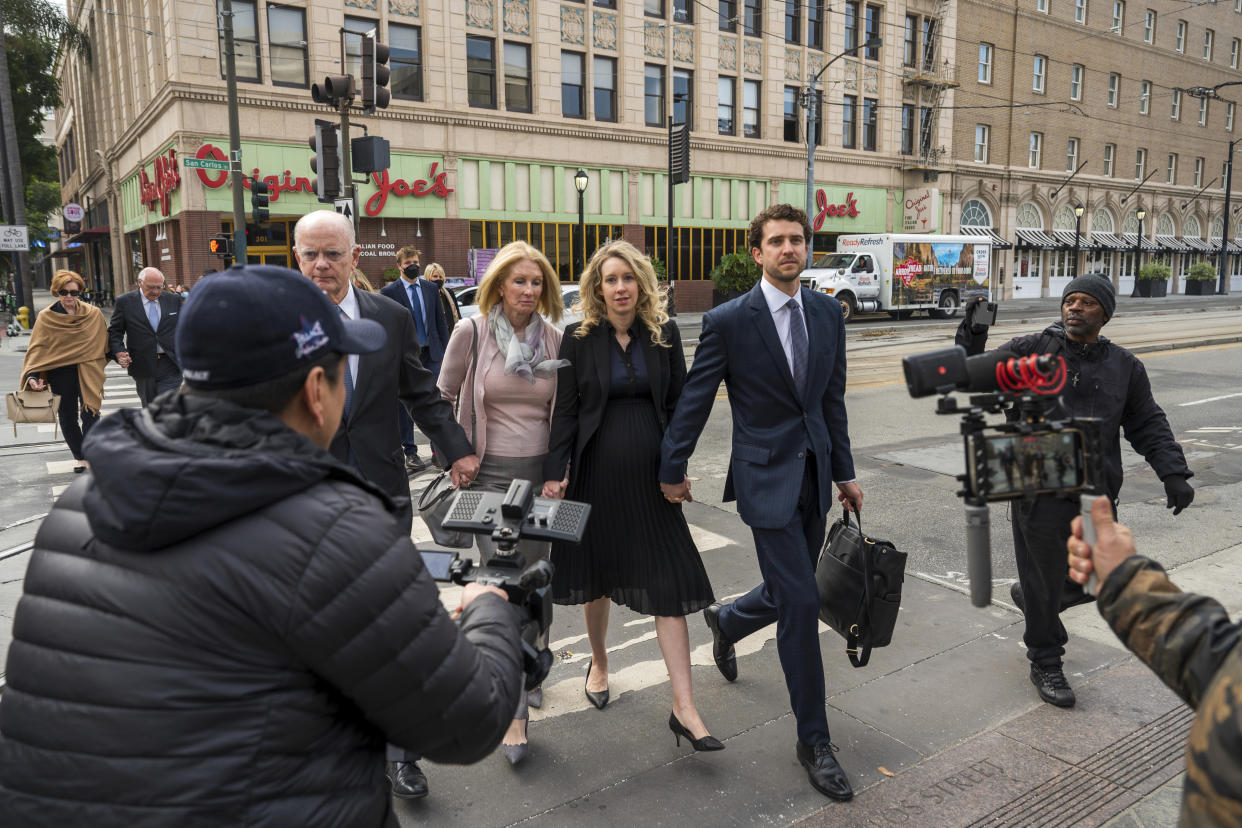 Theranos founder and CEO Elizabeth Holmes, center, walks into federal court with her partner Billy Evans (right) and her parents in San Jose, Calif., Friday, Nov. 18, 2022. A federal judge will decide whether Holmes should serve a lengthy prison sentence for duping investors and endangering patients while peddling a bogus blood-testing technology. (AP Photo/Nic Coury)