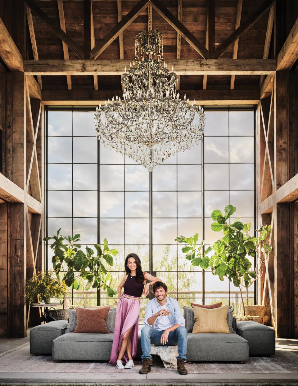 Mila Kunis (wearing a Salvatore Ferragamo outfit, earrings and necklace by Louis Vuitton, a Hoorsenbuhs ring, and Converse sneakers) and Ashton Kutcher (wearing a shirt by Life/After/Denim, a Dolce & Gabbana T-shirt, Levi's jeans and Paul Smith boots) at home in L.A.