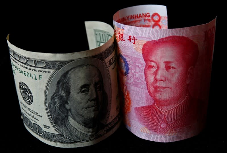 FILE PHOTO: A 100 yuan banknote is placed next to a $100 banknote in this picture illustration taken in Beijing