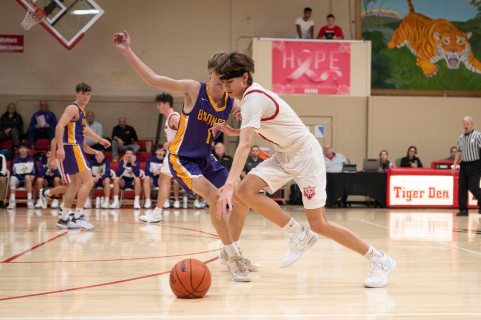 St. Philip sophomore Jackson Dzwik dribbles around Bronson junior Kamron Brackett during the season opening game at St. Philip Catholic Central High School on Tuesday, Nov. 28, 2023.