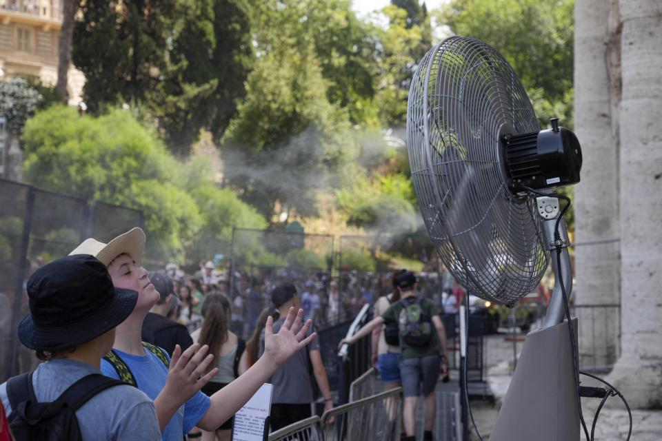 Tourists cool off near a fan as they queue to enter Rome's Colosseum, July 18, 2023. (AP Photo/Gregorio Borgia)