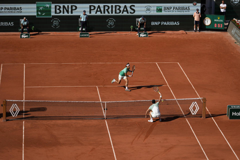 Italy's Lorenzo Musetti, left, runs for the ball to play a shot against Spain's Carlos Alcaraz during their fourth round match of the French Open tennis tournament at the Roland Garros stadium in Paris, Sunday, June 4, 2023. (AP Photo/Thibault Camus)