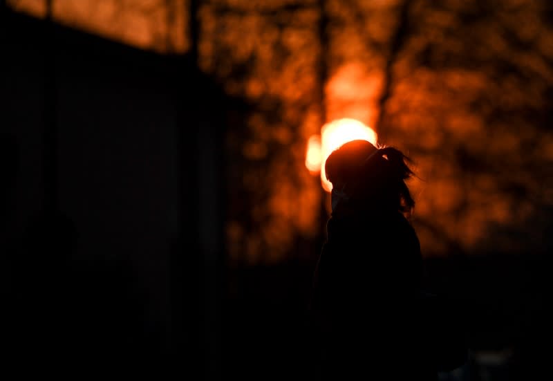 A person wearing a face mask is seen at the sunset as the spread of coronavirus disease (COVID-19) continues, in Milan