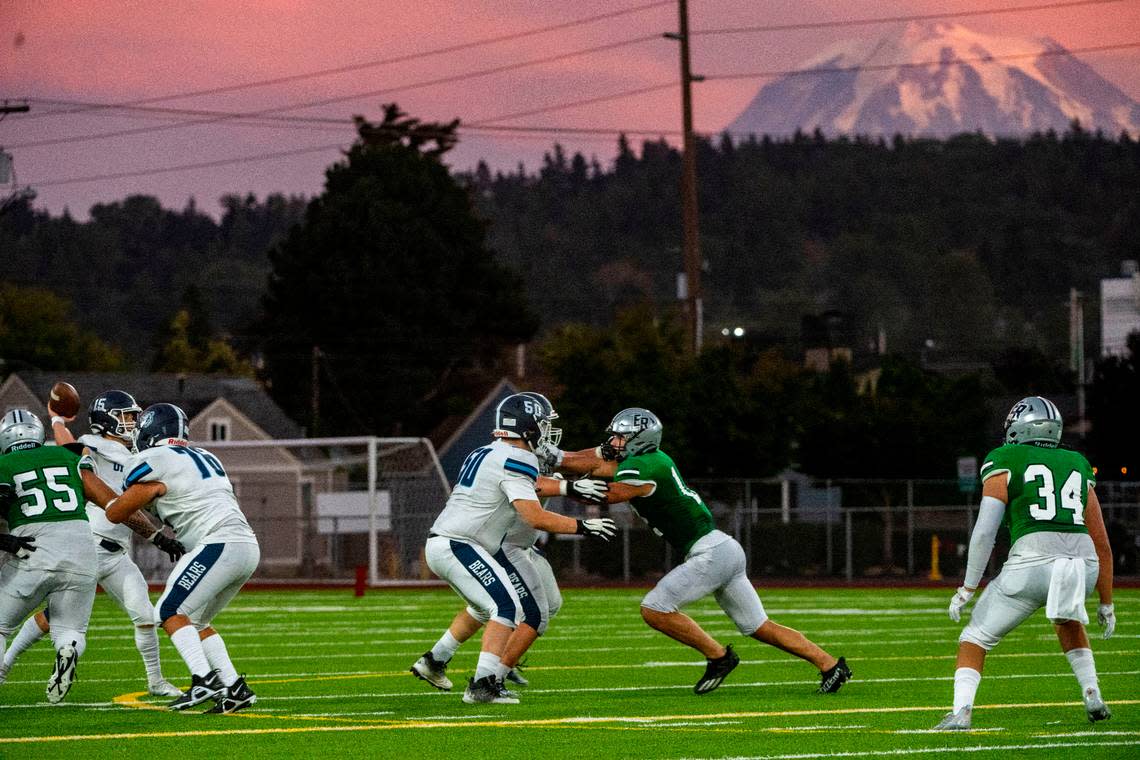 In the background the top of Mt. Rainier is highlighted by the setting sun as Olympia quarterback Gabe Downing attempts a pass during the second quarter of a 4A SPSL game against Emerald Ridge at Sparks Stadium on Thursday, Sept. 8, 2022, in Puyallup, Wash.