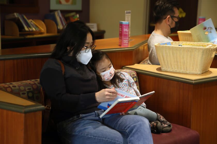 LOS ANGELES, CA - DECEMBER 22: Shelley Kim, left, visiting from Washington D.C., daughter Blythe Kim, 4, and husband Dasol Kim, in the Children's Literature reading room at the Richard J. Riordan Central Library, headquarters of the Los Angeles public library system, in downtown on Thursday, Dec. 22, 2022 in Los Angeles, CA. The Central Library is celebrating its 150th anniversary. Designed by New York architect Bertram Goodhue, the original Central Library was built during the mid-1920s. (Gary Coronado / Los Angeles Times)