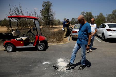 A man stands next to a crater on a road, caused by a rocket fired from the Gaza Strip that landed near it, in a Kibbutz on the Israeli side of the Israeli-Gaza border, June 20, 2018. REUTERS/Amir Cohen