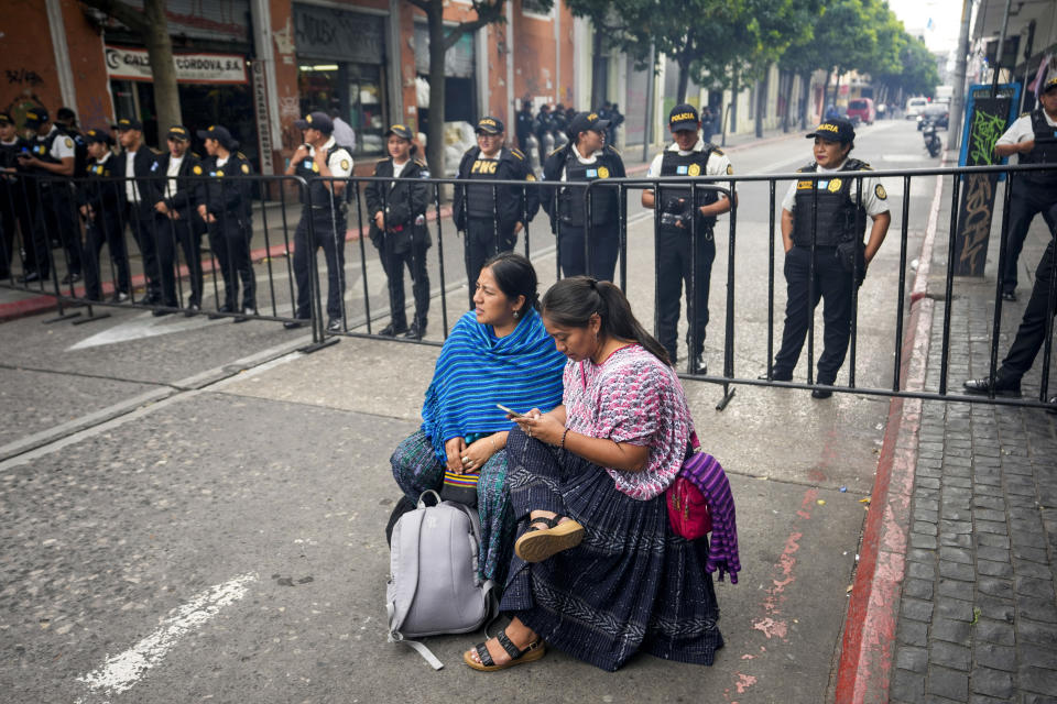 Un par de mujeres manifestantes se sientan frente a la policía cerca del edificio del Congreso en la ciudad de Guatemala, el martes 28 de noviembre de 2023. (AP Foto/Moisés Castillo)