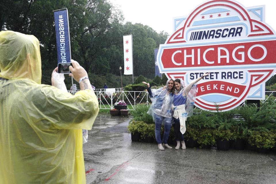 Fans take pictures in the rain before a NASCAR Cup Series auto race at the Grant Park 220 Sunday, July 2, 2023, in Chicago. (AP Photo/Morry Gash)