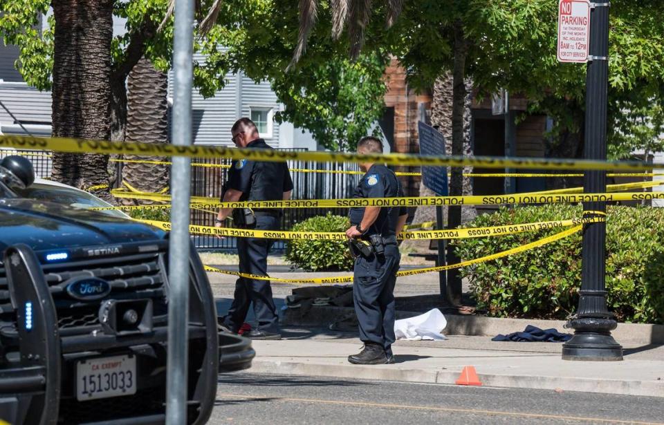 Sacramento police officers on Saturday, May 20, 2023, work near evidence at a cordoned off area at 28th and Q streets, across from Winn Park, following an officer-involved shooting in midtown.