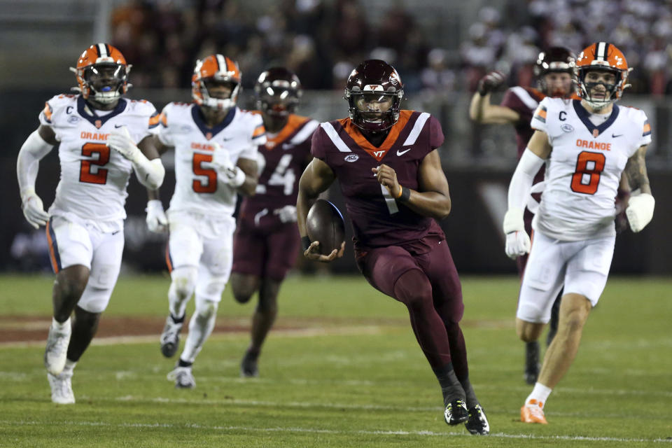 Virginia Tech quarterback Kyron Drones (1) runs for a first down past Syracuse defenders Marlowe Wax (2), Alijah Clark (5) and Justin Barron (8) during the first half of an NCAA college football game in Blacksburg, Va., Thursday, Oct. 26, 2023. (Matt Gentry/The Roanoke Times via AP)