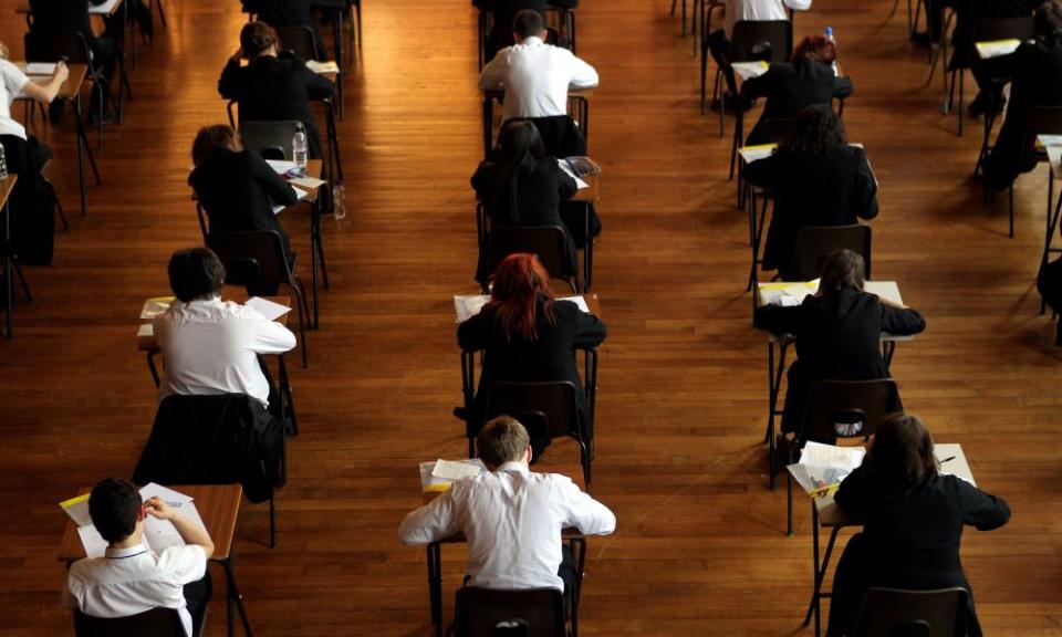 Pupils in a hall sit at rows of desks for a GCSE exam