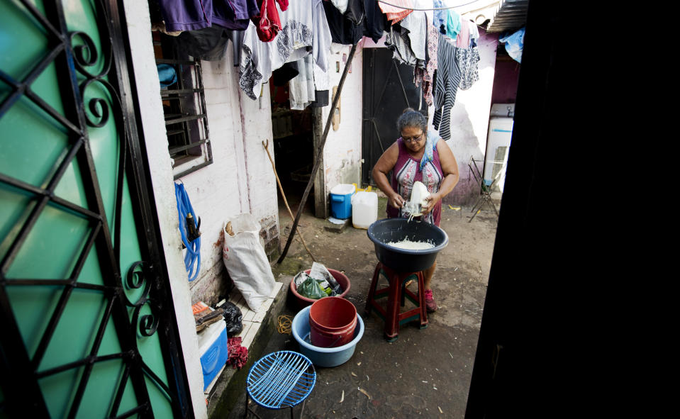 In this Oct. 10, 2019, photo, María Teresa Carballo, cuts cabbage inside of her house in Santa Ana, El Salvador. Like much of Central America’s massive migration of recent years, the driving force behind the Carballo family’s exodus has been fear. Carballo lives in a neighborhood controlled by one gang, but every morning at 5 a.m. she travels to the city’s central market, which is controlled by another gang, to buy yucca, plantains and potatoes to make the fried chips she sells for a living. (AP Photo/Eduardo Verdugo)