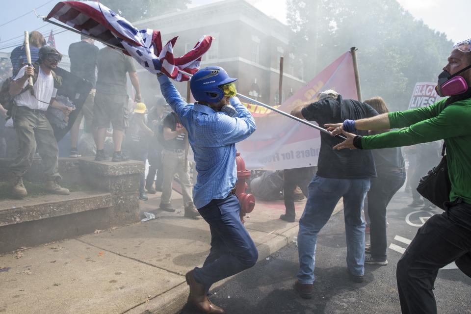 <p>A White Supremacist tries to strike a counter protestor with a White Nationalist flag during clashes at Emancipation Park where the White Nationalists are protesting the removal of the Robert E. Lee monument in Charlottesville, Va., on Aug. 12, 2017. (Photo: Samuel Corum/Anadolu Agency/Getty Images) </p>