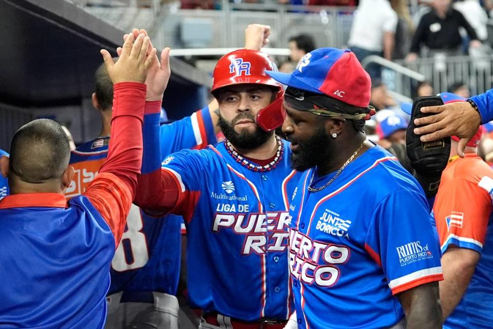 El tercera base de Puerto Rico Emmanuel Rivera (centro) es felicitado tras anotar una carrera ante Venezuela, en la segunda entrada del partido de la Serie del Caribe, celebrado el domingo 4 de febrero de 2024 en Miami.