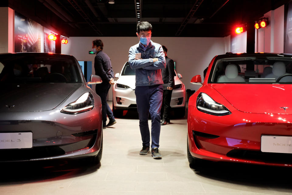 A man wearing a face mask following the coronavirus disease (COVID-19) outbreak walks by Tesla Model 3 sedans and Tesla Model X sport utility vehicle at a new Tesla showroom in Shanghai, China May 8, 2020. Picture taken May 8, 2020. REUTERS/Yilei Sun - RC2TMG9NGD7E