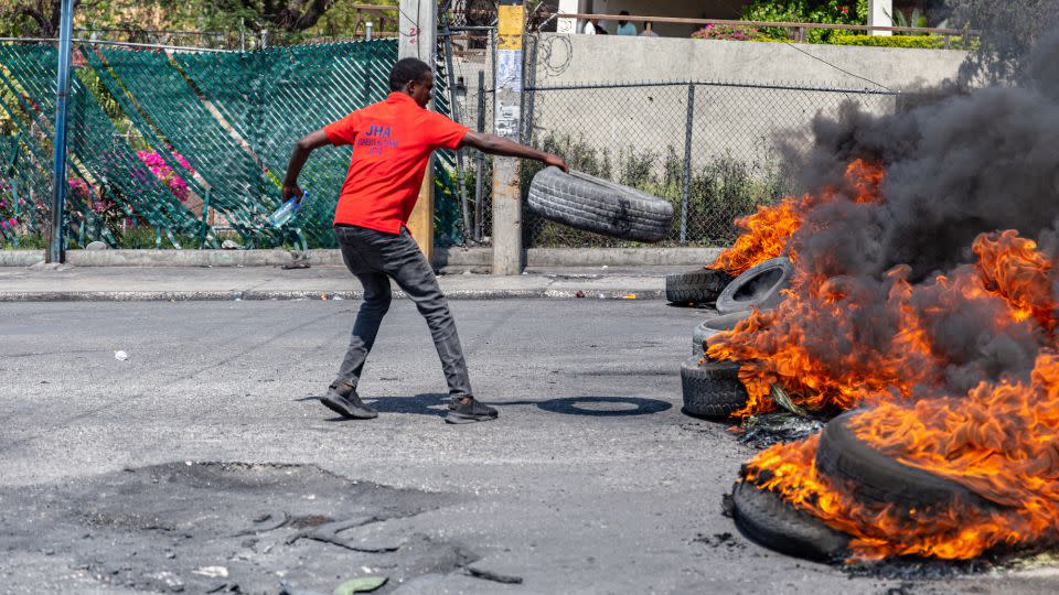 A man sets a tire on fire during a demonstration following the resignation of Haitian Prime Minister Ariel Henry. - Guerinault Louis/Anadolu Agency/Getty Images