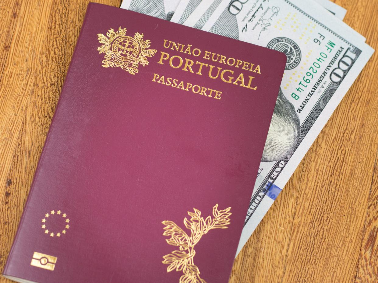 Portuguese passport (Translation "European Union Portugal passport") and one hundred dollar banknotes wooden background