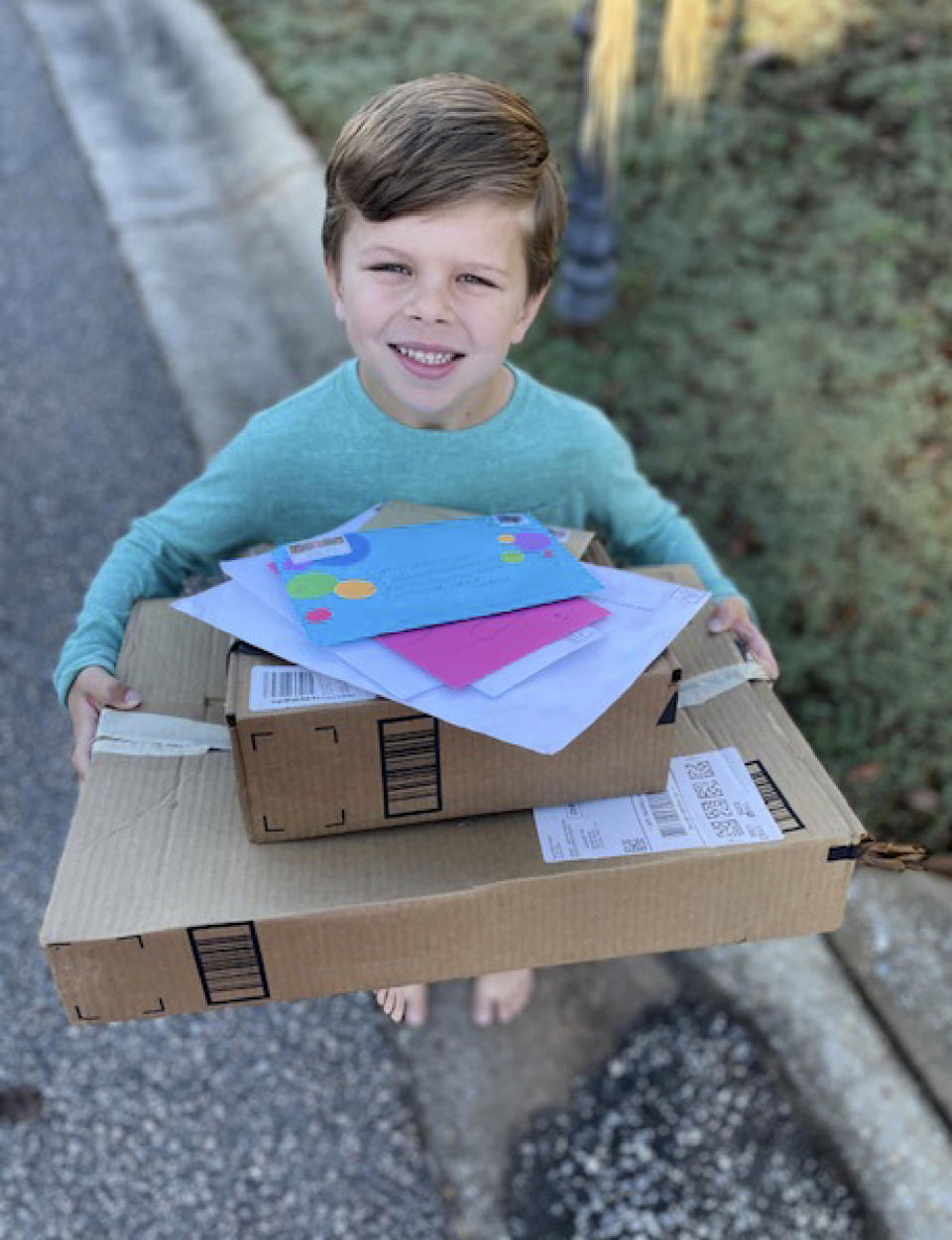 Chip Matthews, 6, holds a stack of birthday presents delivered to his home in Opelika, Ala., on Thursday, Nov. 5, 2020. Matthews was given an extra birthday surprise when postal worker, Tawanna Purter, gave him $2 as a gift. (Bonnie Matthews via AP)