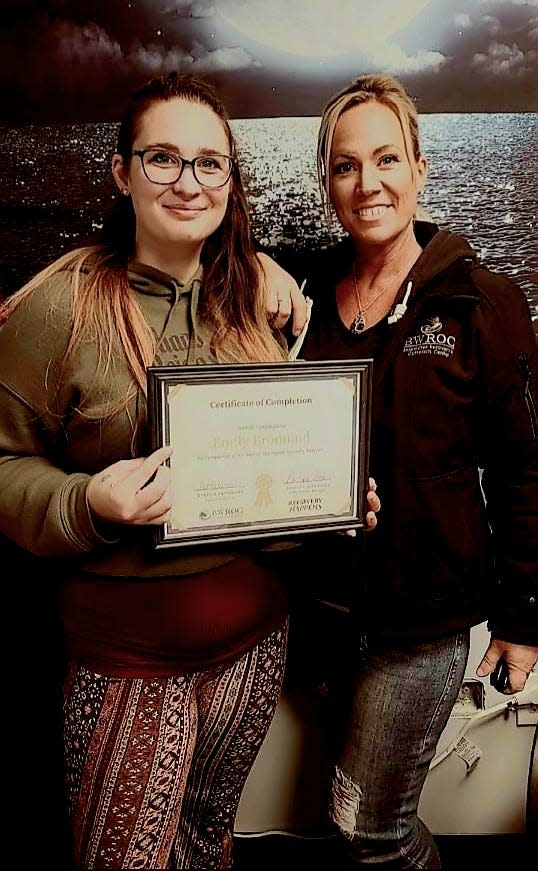 Emily Bromund, left, holds her certificate for completing Blue Water Recovery and Outreach Center's program, with Barb Alexander, recovery coach and center manager.