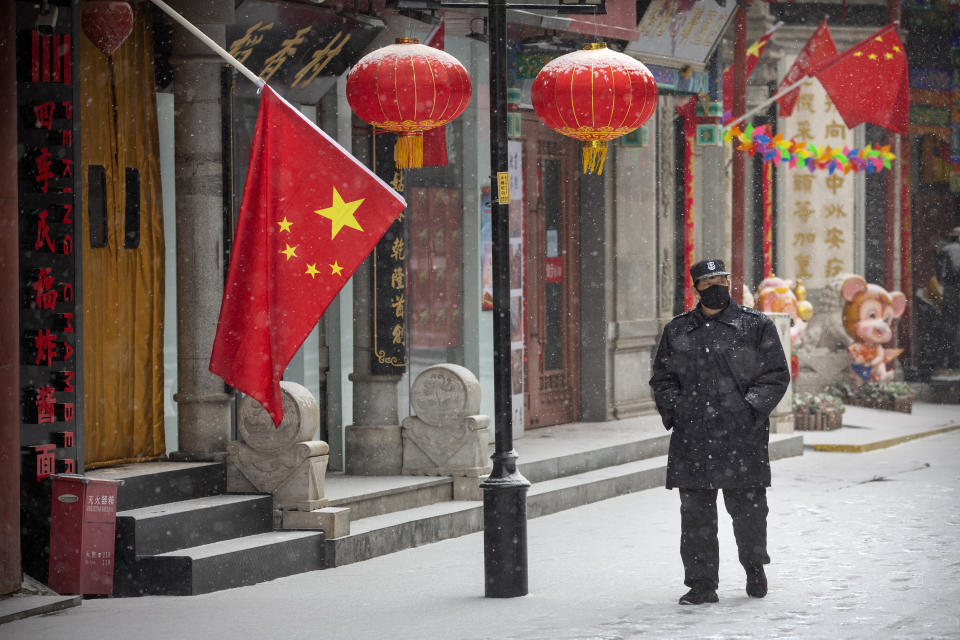 A security guard wears a face mask as he walks along a pedestrian shopping street during a snowfall in Beijing, Wednesday, Feb. 5, 2020. Deaths from a new virus rose to 490 in mainland China on Wednesday while new cases on a Japanese cruise ship, in Hong Kong and in other places showed the increasing spread of the outbreak and renewed attention toward containing it. (AP Photo/Mark Schiefelbein)