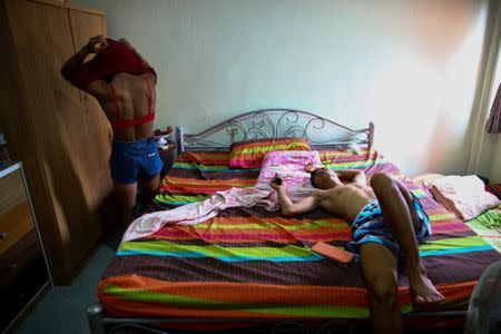 Muay Thai boxer Nong Rose Baan Charoensuk, 21, who is transgender, changes her shirt as her boyfriend Beer rests on a bed, in a room at the Baan Charoensuk gym in Chachoengsao province, Thailand, July 12, 2017. REUTERS/Athit Perawongmetha