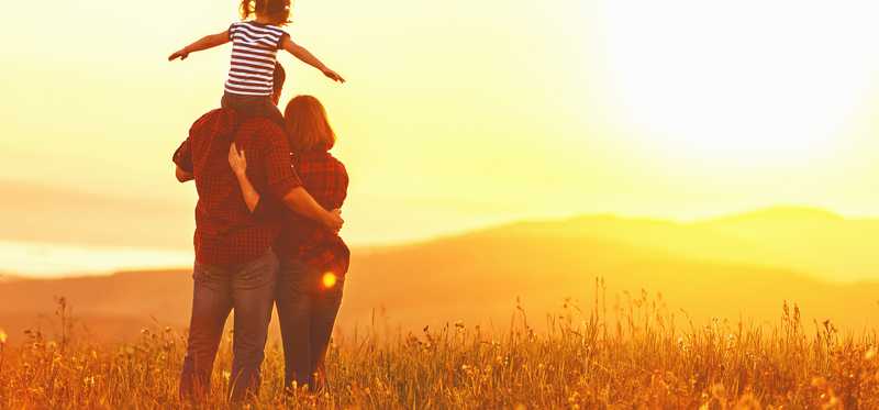 A family standing in a pasture looking at the horizon.