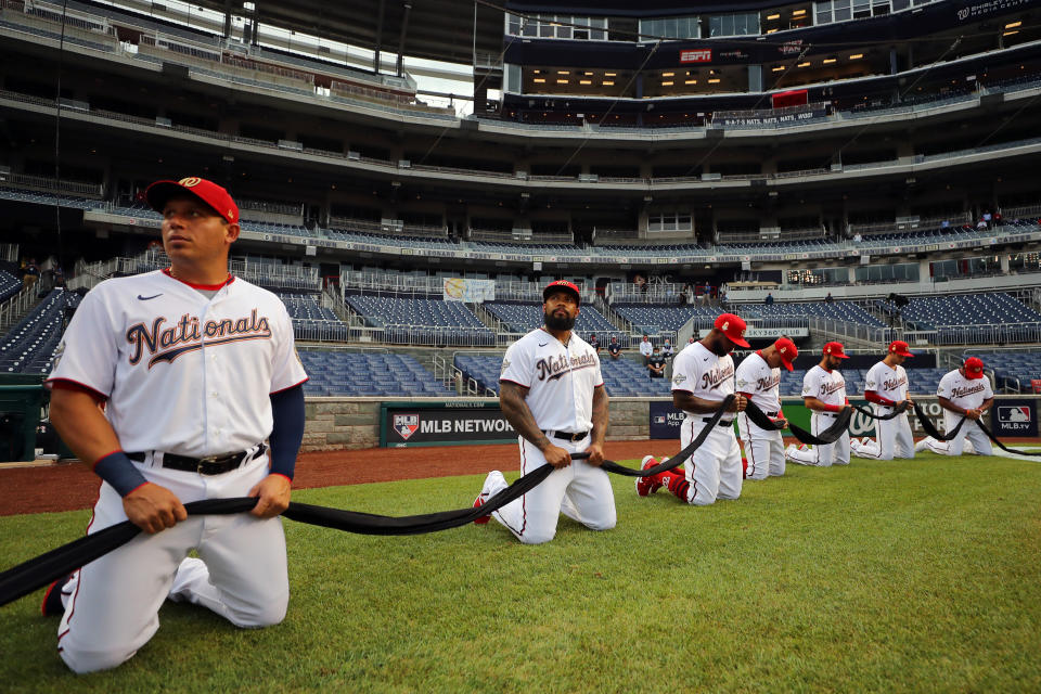 WASHINGTON, DC - JULY 23:  Members of the Washington Nationals kneel and hold a black ribbon to show their support for social justice and diversity and inclusion in baseball and life during the pre-game ceremony prior to the game between the New York Yankees and the Washington Nationals at Nationals Park on Thursday, July 23, 2020 in Washington, District of Columbia. (Photo by Alex Trautwig/MLB Photos via Getty Images)