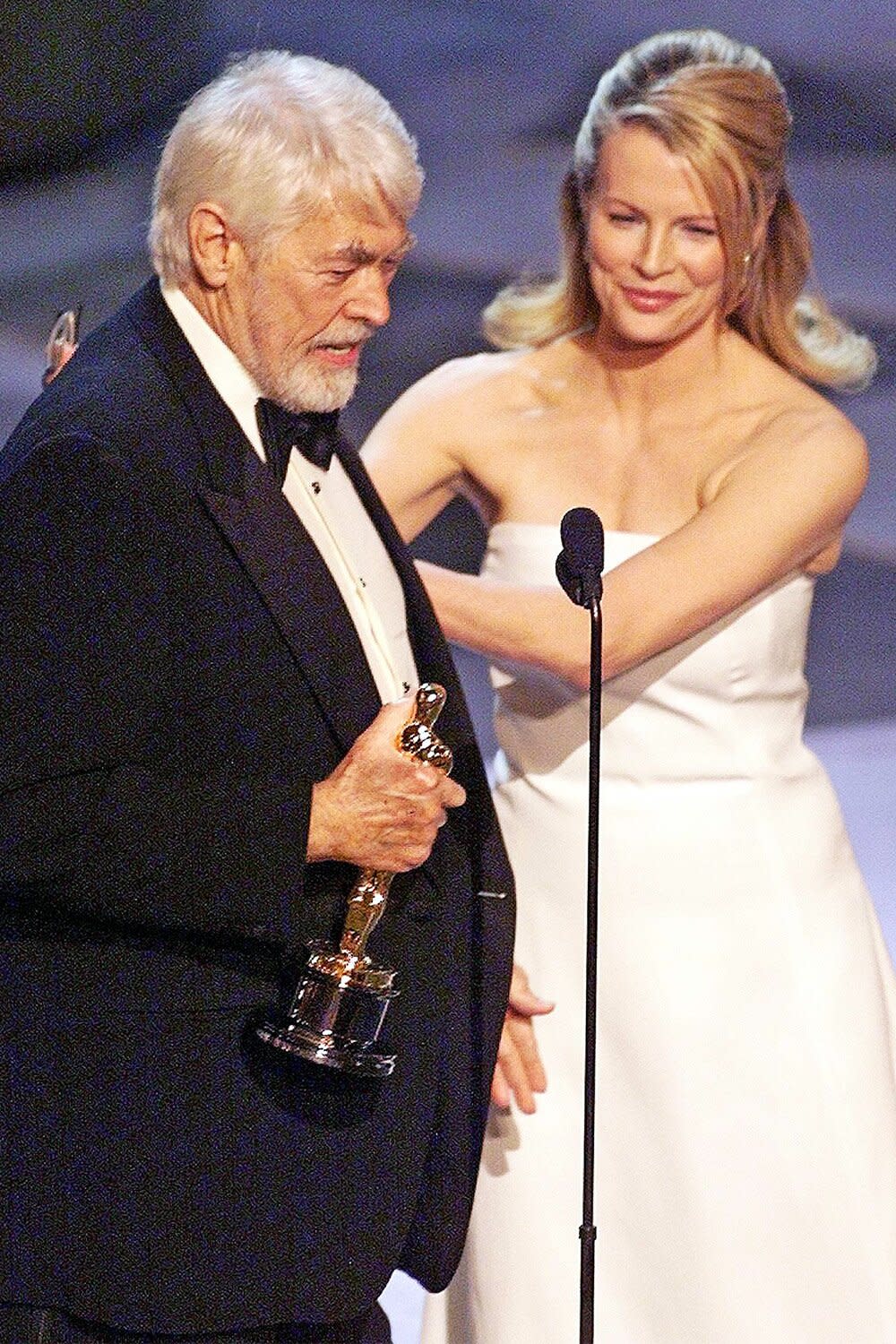 James Coburn holds up his Oscar after winning for Best Performance by a Supporting Actor in a Leading Role for his part in the movie "Affliction" during the 71st Academy Awards 21 March 1999 at the Dorothy Chandler Pavilion. Presenting the Oscar is Kim Basinger. (ELECTRONIC IMAGE) AFP PHOTO/Timothy A. CLARY (Photo by Timothy A. CLARY / AFP) (Photo by TIMOTHY A. CLARY/AFP via Getty Images)