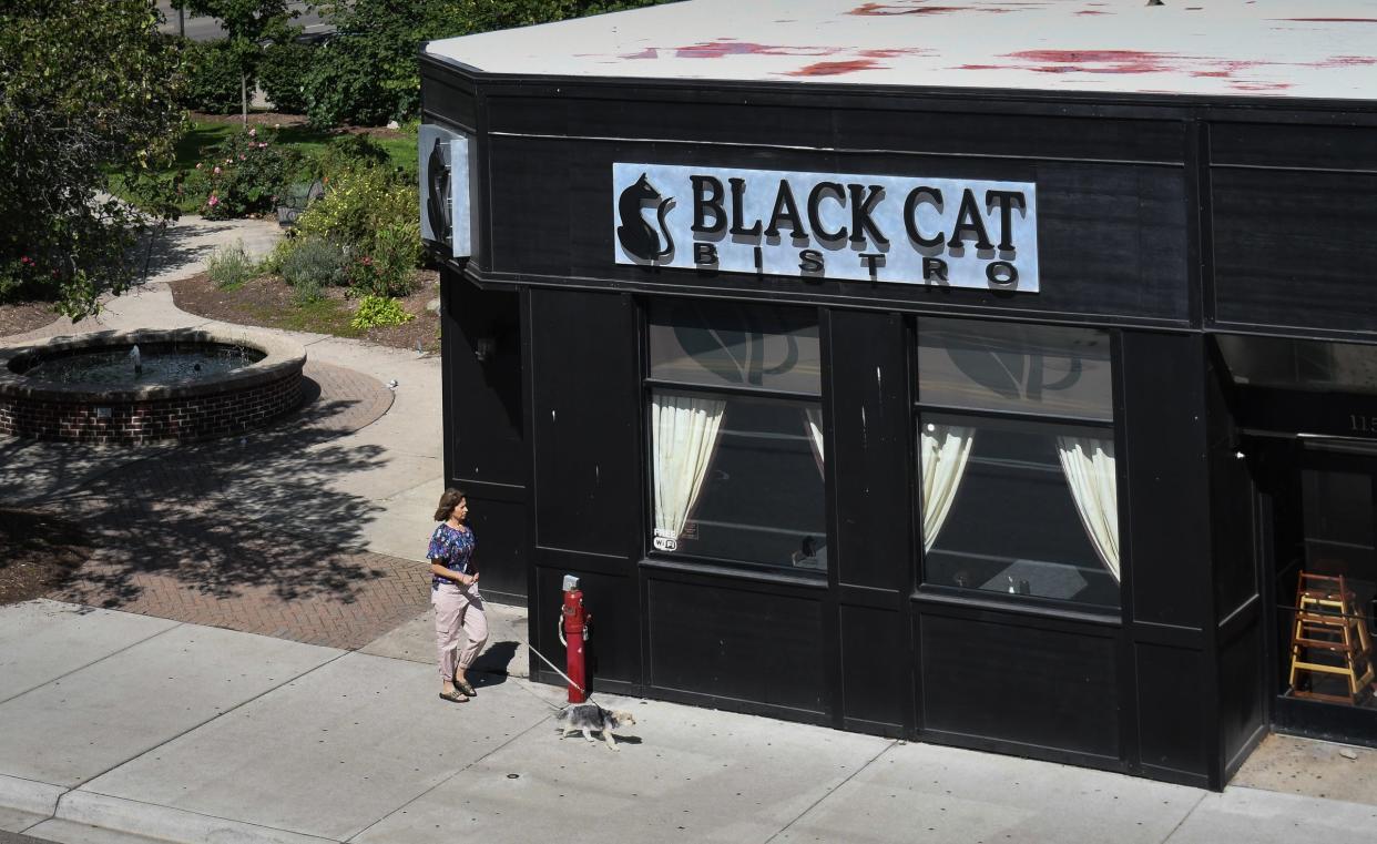 A woman and her dog pass by the Black Cat Bistro in East Lansing, Friday, Sept. 15, 2023.