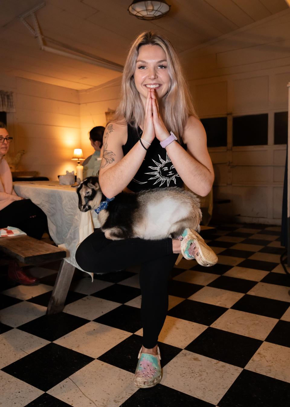 Yoga instructor Jessica Lescrinier performs a one-legged chair pose with Pepper the goat at Wine-yasa Goat Yoga night at Legacy Lane Farm in Stratham.