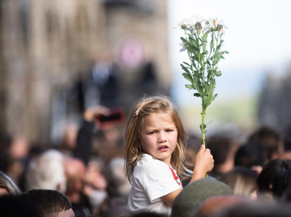 EDINBURGH, SCOTLAND - SEPTEMBER 12: A girl looks on ahead of the arrival of the Royals at a service at St Giles Cathedral on September 12, 2022 in Edinburgh, Scotland. King Charles III joins the procession accompanying Her Majesty The Queen's coffin from the Palace of Holyroodhouse along the Royal Mile to St Giles Cathedral. The King and The Queen Consort, accompanied by other Members of the Royal Family also attend a Service of Prayer and Reflection for the Life of The Queen where it lies in rest for 24 hours before being transferred by air to London.