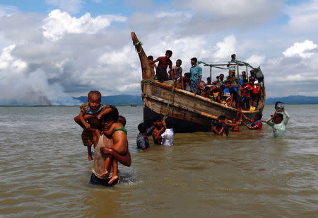 Smoke is seen on Myanmar's side of border as Rohingya refugees get off a boat after crossing the Bangladesh-Myanmar border through the Bay of Bengal in Shah Porir Dwip, Bangladesh September 11, 2017. REUTERS/Danish Siddiqui