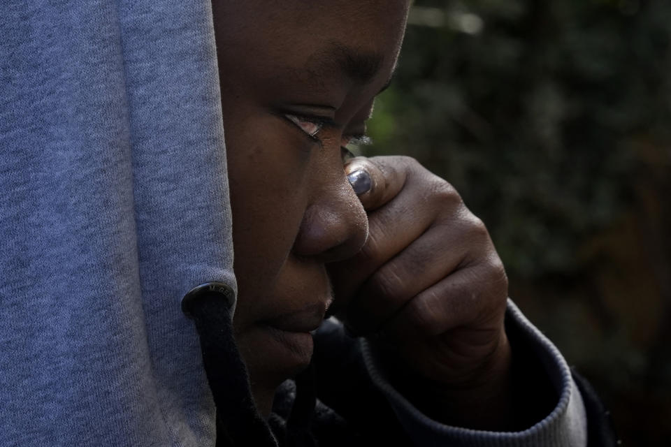 Grace Enjei, 24, a migrant from Cameroon, wipes her tears next to a tent behind the House of Cooperation located inside a United Nations-controlled buffer zone cutting across Nicosia, the capital of ethnically divided Cyprus on Wednesday, Dec. 1, 2021. The Cameroonian asylum seekers crossed from the island's breakaway Turkish Cypriot north about six months ago and got stuck in the buffer zone amid a Cypriot government crackdown on migrants crossing the porous buffer zone. (AP Photo/Petros Karadjias)