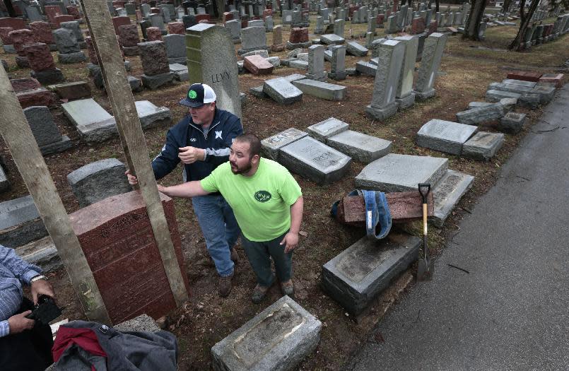 Spencer Pensoneau, center, and Ron Klump of Rosenbloom Monument Company re-set stones at Chesed Shel Emeth Cemetery in University City, mMo., on Tuesday, Feb. 21, 2017 where almost 200 gravestones were vandalized over the weekend. (Robert Cohen/St. Louis Post-Dispatch via AP)