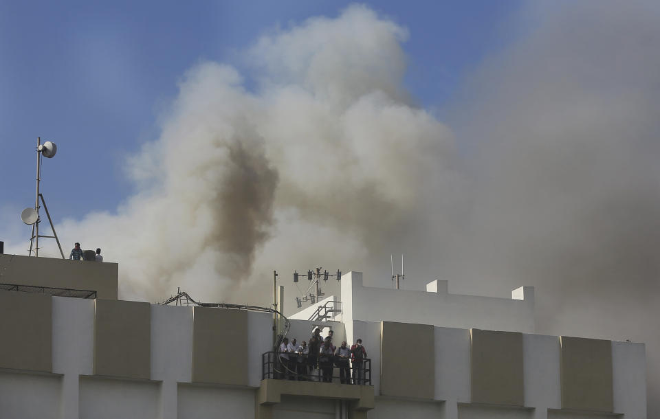 People awaiting rescue stand on the balcony of a nine-story building with offices of a state-run telephone company during a fire in Mumbai, India, Monday, July 22, 2019. (AP Photo/Rafiq Maqbool)