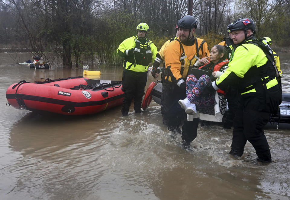 Beaver Falls, Pa., firefighter Jason Tyger, right, gets some help carrying a woman from a boat after she was rescued from her flooded home on McKim Way in Franklin Township, Pa., Wednesday, April 3, 2024. (Lucy Schaly/Pittsburgh Post-Gazette via AP)